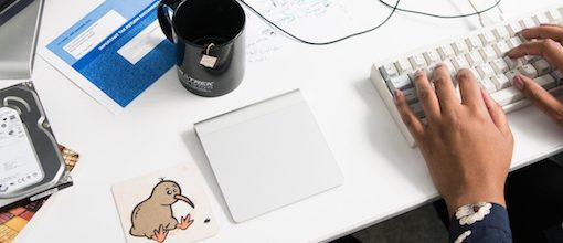 Desk with hard drives, a smart mouse, and keyboard with a woman's hands typing
