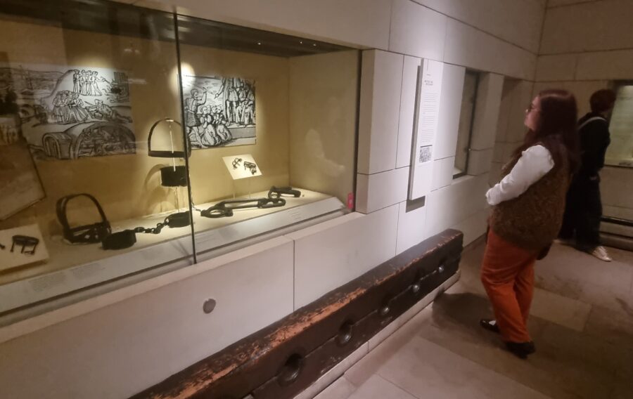 Dervla Craig standing looking at the Scottish witch trials exhibit at the National Museum of Scotland.